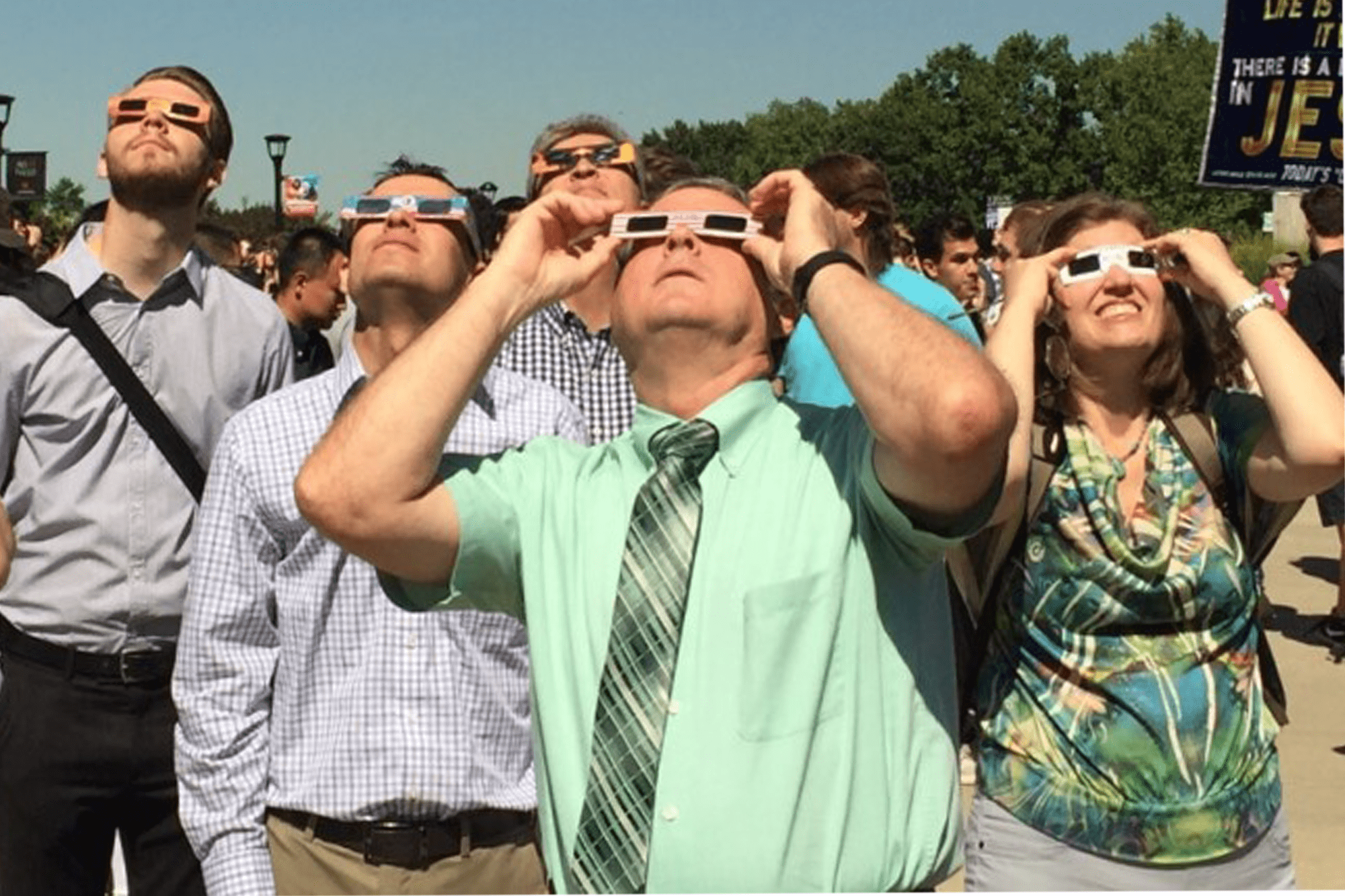 Retro image of people in business casual looking at the sky with eclipse safety glasses